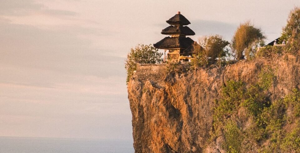 brown wooden house on brown rock formation near body of water during daytime