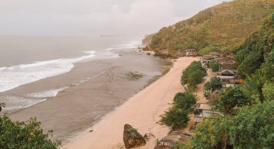 Breathtaking view of a tropical beach in Yogyakarta, Indonesia, with lush green hills and tranquil waves.