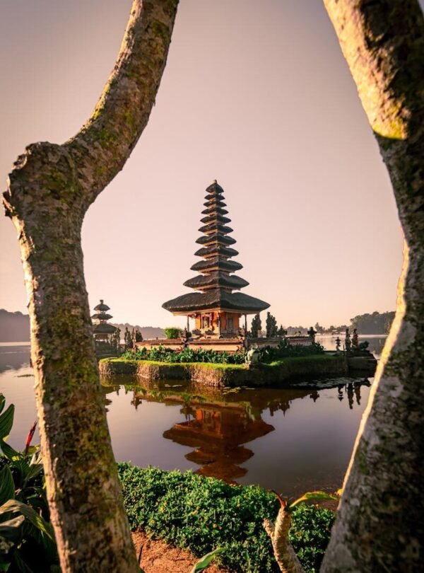 Scenic view of Ulun Danu Beratan Temple, Bali, reflecting in calm water during sunrise.