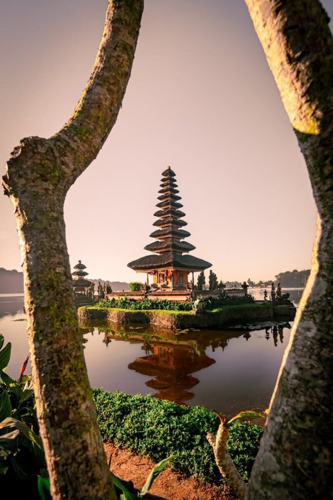 Scenic view of Ulun Danu Beratan Temple, Bali, reflecting in calm water during sunrise.