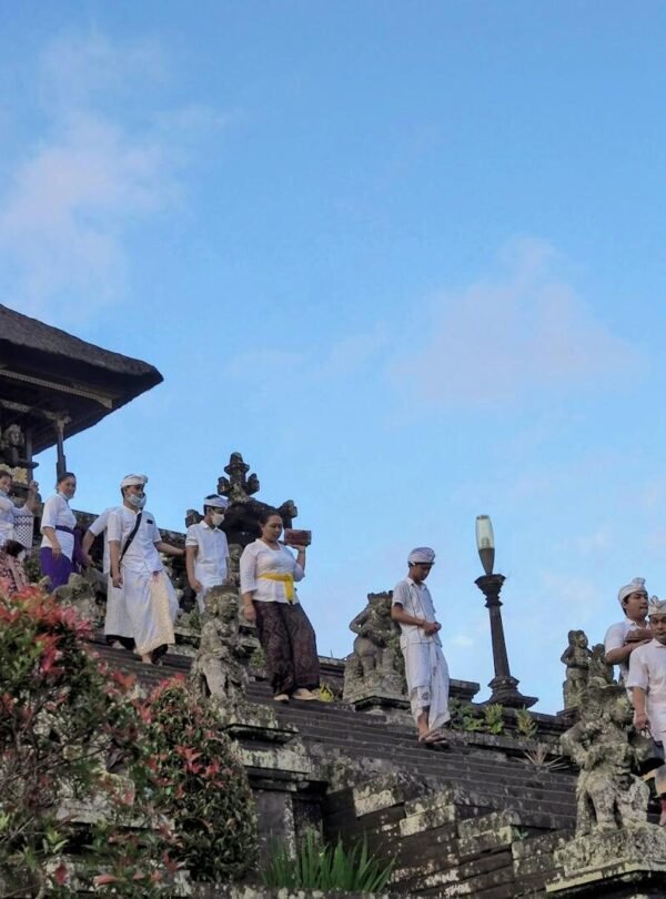 People in traditional attire at the iconic Besakih Temple in Bali, Indonesia, during a cultural ceremony.