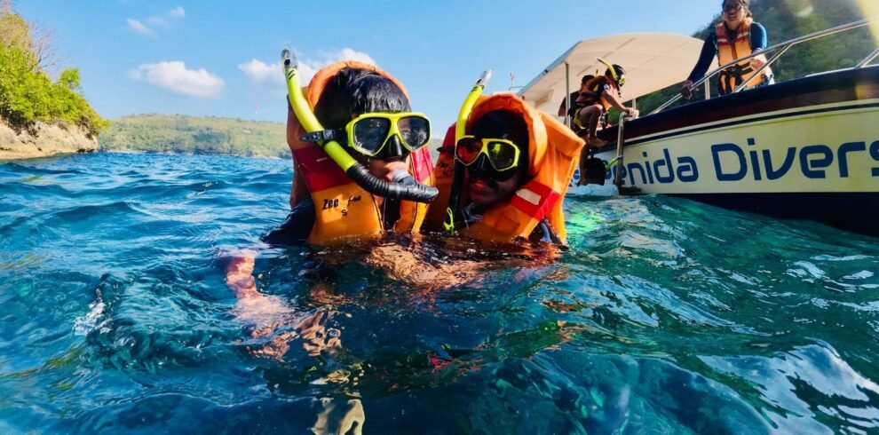 Two children snorkeling near Nusa Penida in Bali with life jackets and snorkel gear.