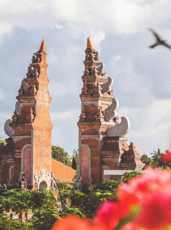 The split gate of a Balinese temple in Bali, Indonesia, with blurred flowers